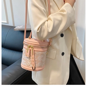 Nahaufnahme der rosa Beuteltasche mit Blumenstickerei und goldenen Beschlägen am Blazer