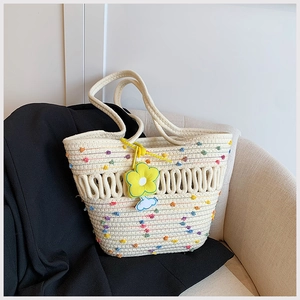 Détail du sac cabas tressé ivoire avec nœuds colorés et breloque fleur de tournesol