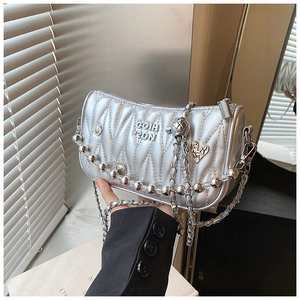 Detail of silver quilted handbag featuring beaded chain and metallic V-pattern texture