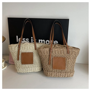 Detail of woven straw tote bags featuring leather handles and drawstring lining closure