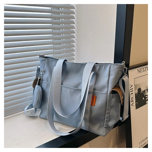 Detailed close-up of a light blue canvas tote bag with orange label and mini round pouch
