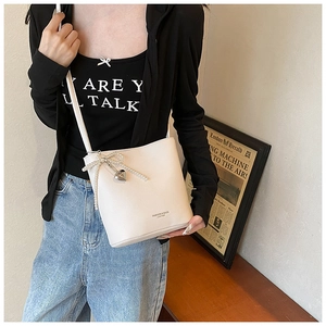 Detail of cream white leather bucket bag with pearl bow and silver heart pendant