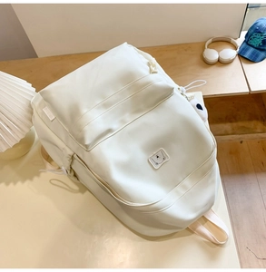 Detail of cream white large-capacity backpack with cute bear patch and side logo label
