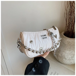 Detail of white quilted barrel bag featuring silver metal charms and chain strap