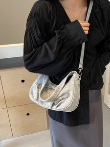 Silver textured crescent handbag with bow accents and adjustable strap shown on model