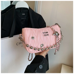 Pink quilted crossbody bag with silver punk chains and skull tassel detail in scene