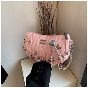 Close-up of pink quilted crossbody bag with metallic heart charms and chain strap detail