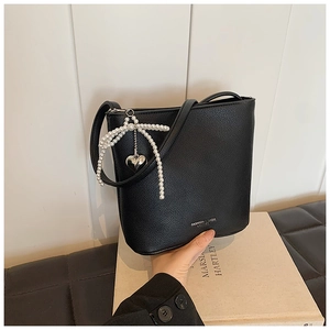 Detail of black pebbled leather bucket bag with pearl bow and silver heart charm