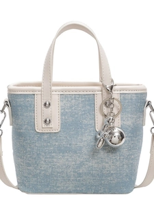 Blue denim tote bag with silver studs and balloon dog charm on white background