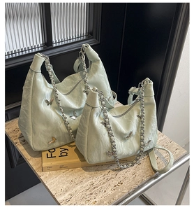 Detail of soft mint green tote bag with pleated leather texture and silver butterflies