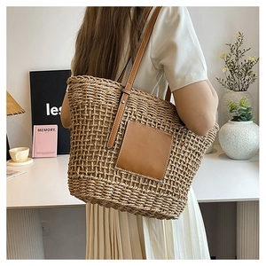 Macro detail of hand-woven straw tote with premium brown leather patch and straps