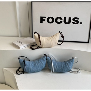 Detailed view of croissant-style crescent bags in denim blue and off-white on display