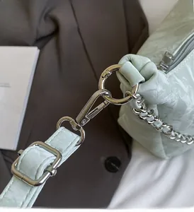 Detail of glossy mint green textured fabric with premium silver chain hardware link