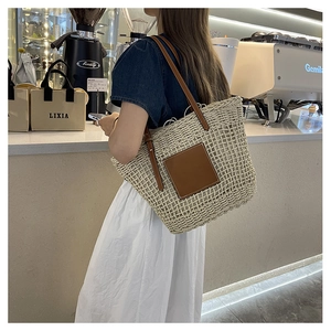 Detail of handwoven white straw tote bag with brown leather straps and square patch