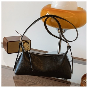 Detail of black vintage pleated underarm bag with oil-wax texture and silver zipper