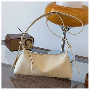 Detailed view of cream-colored baguette bag with pleated texture and embossed logo