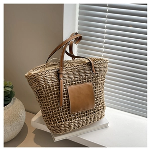 Detailed shot of woven straw tote bag with brown leather handles and drawstring lining