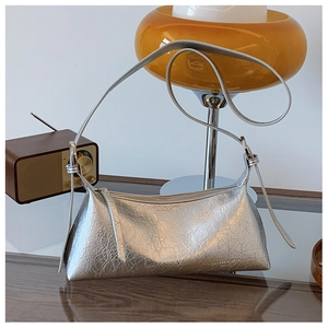 Detail of silver metallic underarm bag with pleated texture on a vintage wooden desk