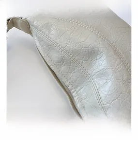 Detailed close-up of cream white dumpling bag showing soft quilted faux leather texture