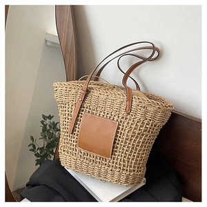 Detail of the woven straw tote bag featuring leather shoulder straps and drawstring lining