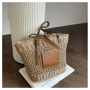 Detail of woven straw tote bag with brown leather handle and rustic grid texture