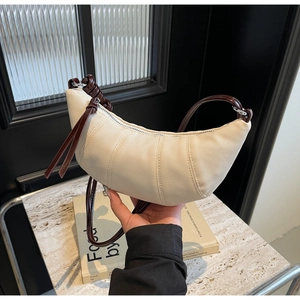 Detailed view of cream canvas croissant bag with contrast dark brown leather strap