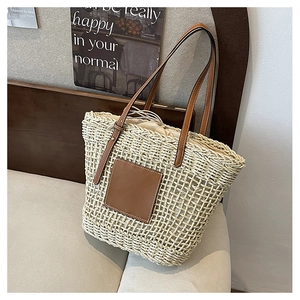 Detail of woven straw tote bag with brown leather straps and drawstring inner liner