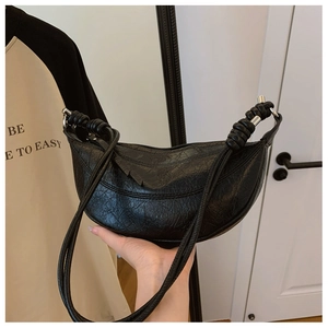Detailed close-up of a black pleated crescent bag with silver rings and knot details