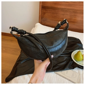 Close-up of black pleated dumpling bag with knot detail and sleek metal hardware