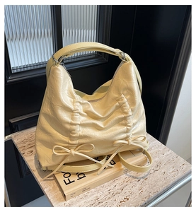 Dettaglio della borsa hobo giallo crema con trama a pieghe e decorazione con fiocco
