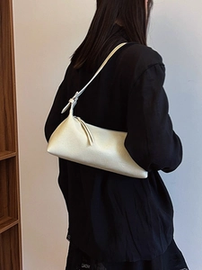 Minimalist cream white baguette shoulder bag in matte leather worn with black outfit