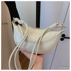 Detailed view of the creamy white half-moon bag featuring a knotted handle and vintage texture