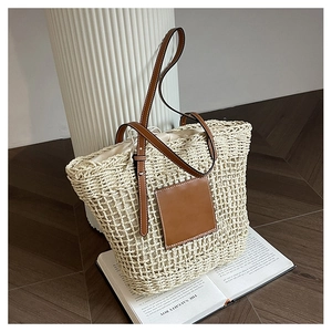 Detail of woven straw tote bag with brown leather straps and drawstring inner pocket