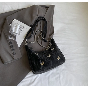 Detail of black pleated shoulder bag with silver butterfly charms and metal chain strap