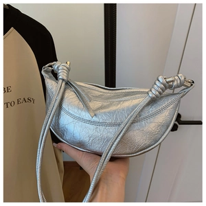 Detailed close-up of a metallic silver croissant bag with a stylish knotted strap design