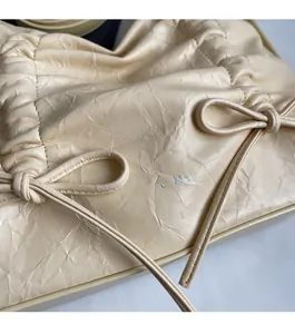Dettaglio della borsa in pelle increspata bianco crema con coulisse decorativa e texture