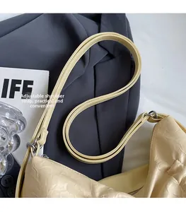 Dettaglio della tracolla regolabile con fibbia argentata su borsa in pelle crema