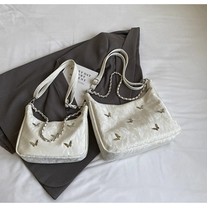 Detail of hobo bag featuring silver butterfly charms and ivory wrinkled texture leather
