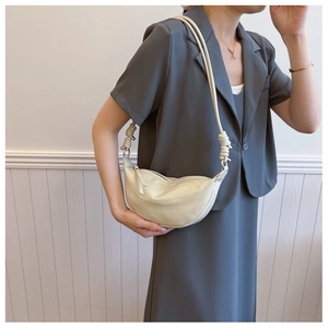 Detail of knot design on beige crescent shoulder bag with soft textured leather finish