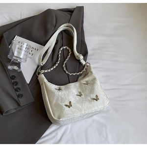 Detail of off-white hobo bag with textured fabric and five silver metal butterfly charms