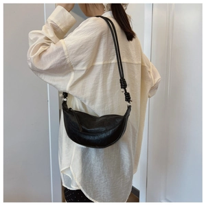 Detail of black crescent shoulder bag featuring knotted strap and silver hardware