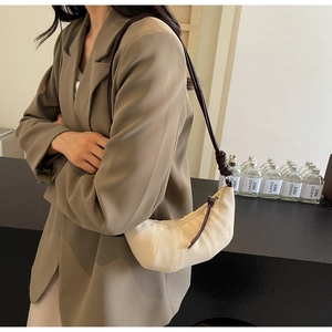 Detail of cream canvas croissant bag with brown leather knotted strap and zip closure