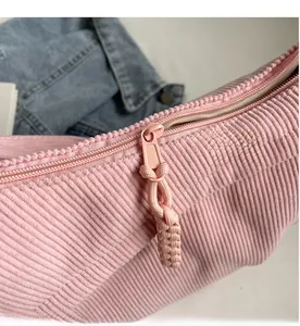 Close-up of smooth pink zipper and woven puller on pink corduroy crossbody bag