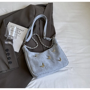Detail of grey shoulder bag with gold butterfly accents and textured pleated fabric