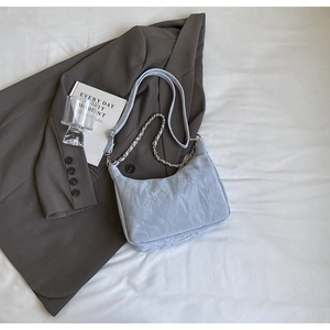 Detail of light blue pleated shoulder bag with silver chain strap and wide strap