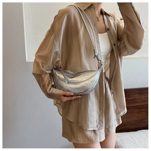 Detail of metallic silver crescent bag featuring pleated faux leather and knot strap