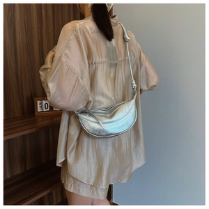 Detail of silver metallic crescent bag showing its pleated texture and knotted strap
