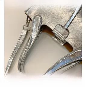 Detail of silver metallic textured handbag featuring pleated finish and leather inner lining