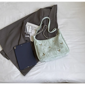 Detailed view of mint green pleated shoulder bag with gold butterfly clips and chain strap
