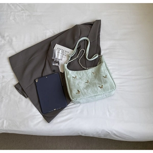 Detail view of mint green hobo bag with gold butterfly accents and chain strap